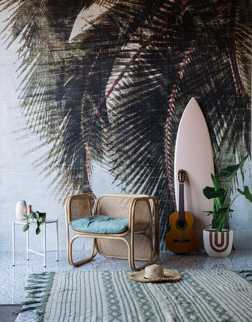 Rattan armchair and surfboard against a palm tree wall