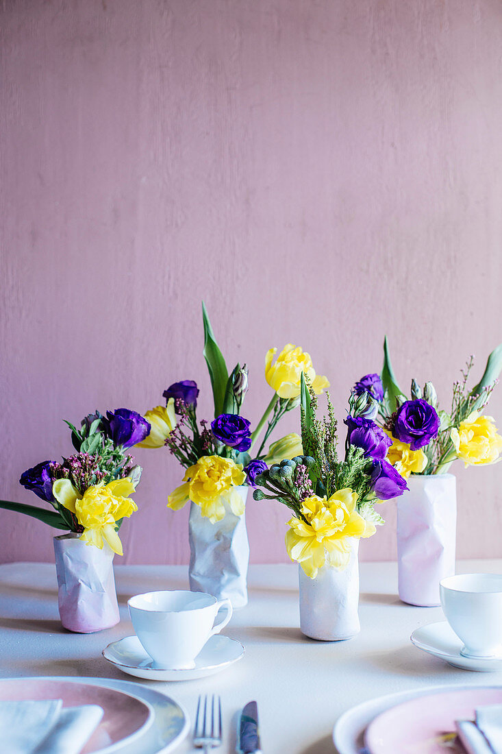 Spring flowers in three vases shaped like crushed tin cans