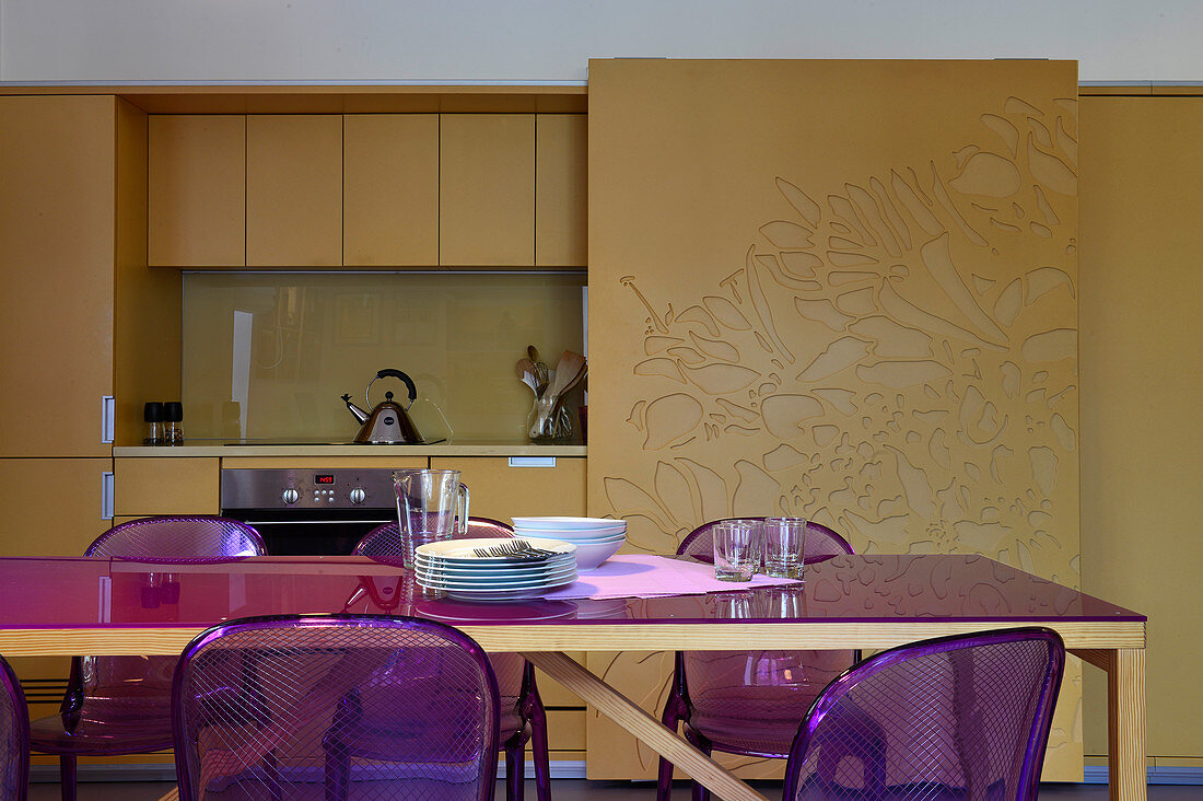 Esstisch mit Stühlen in Violett vor der Küchenzeile mit Schiebetüren