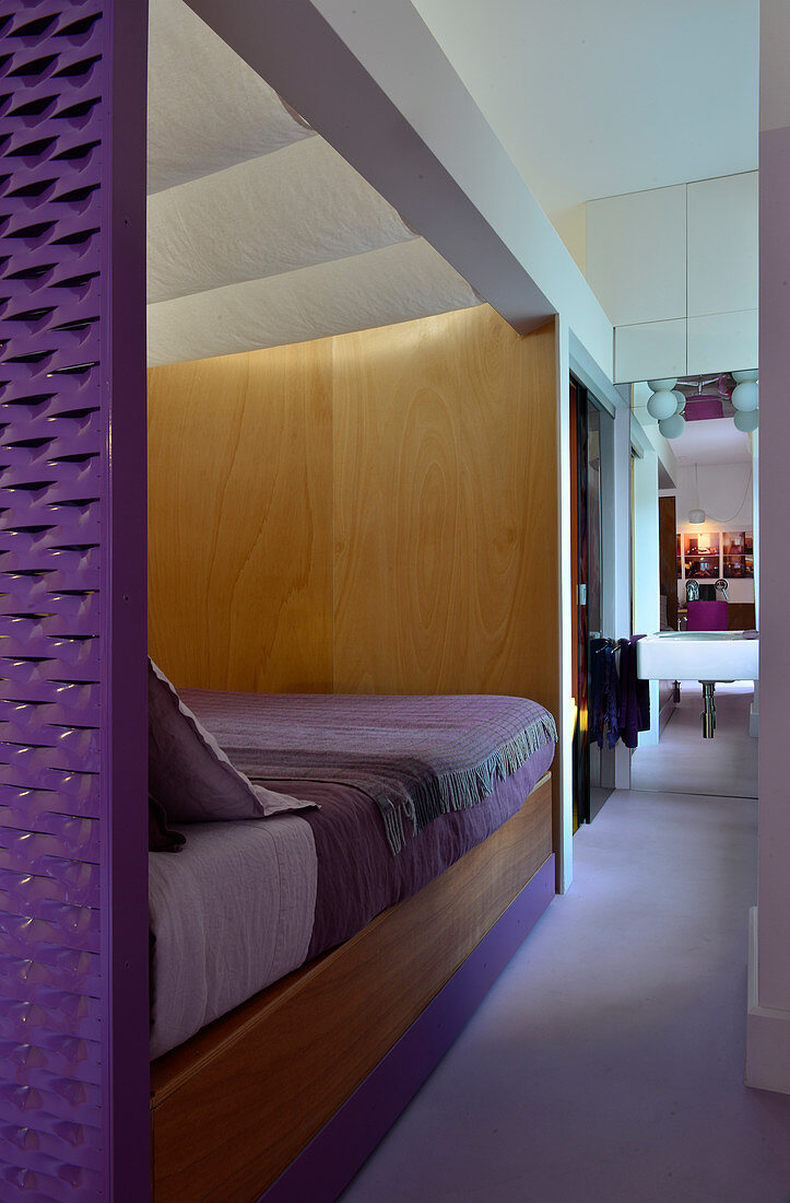 Bed hidden by partition wall, ensuite bathroom and purple accents