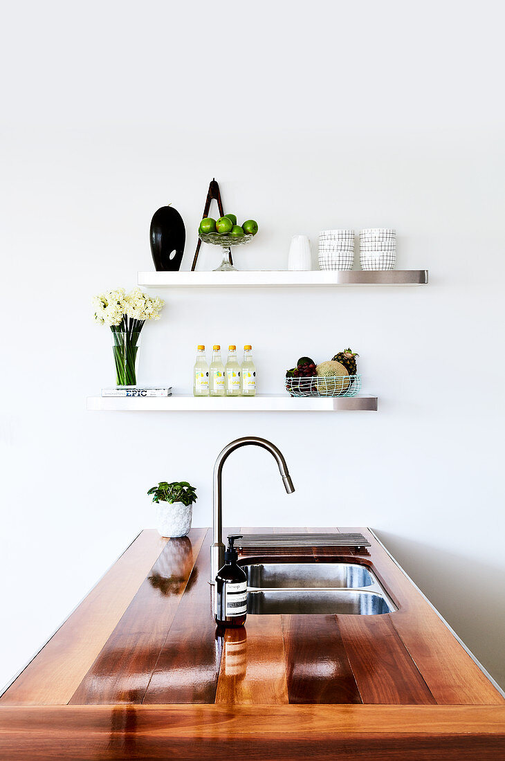 Island counter with wooden worksurface and sink in white kitchen