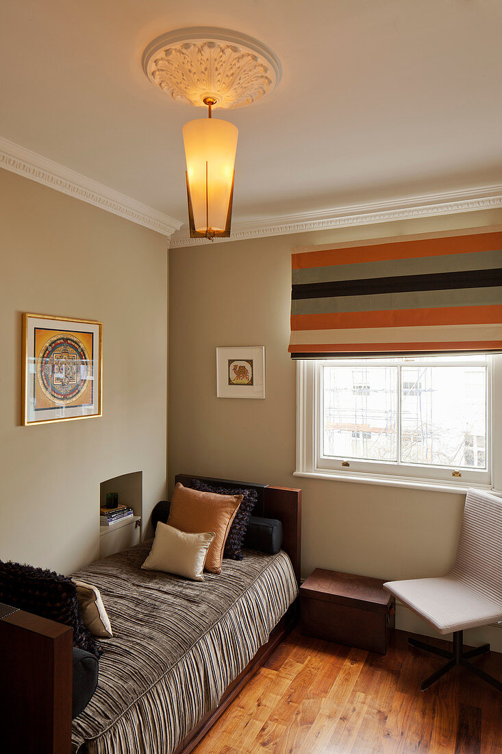 Modern lamp hung from stucco rosette above single bed