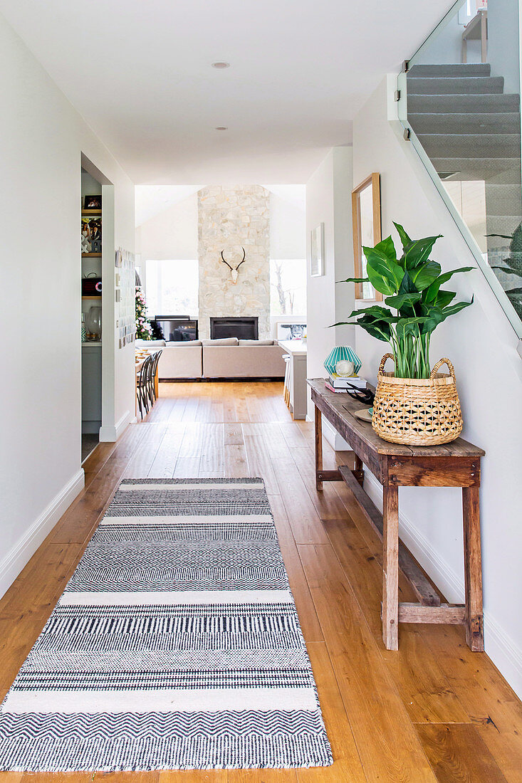 Flur zum offenen Wohnzimmer mit langem Teppich und altem Holztisch