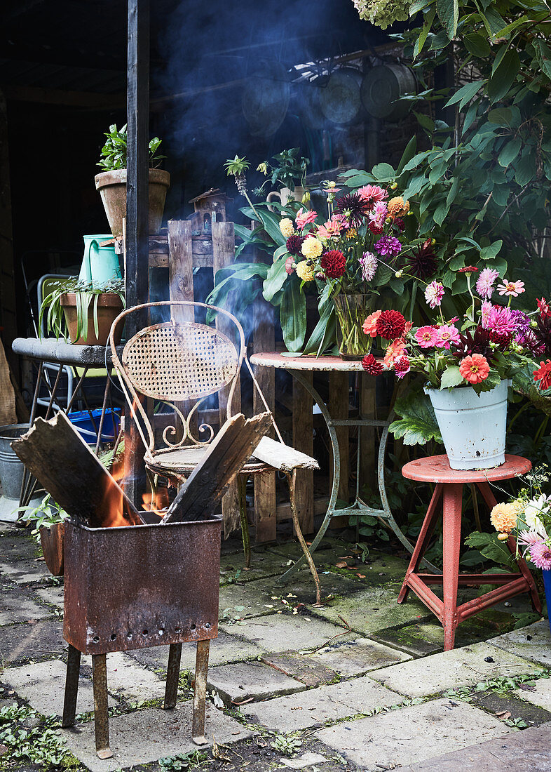 Brazier in front of vases of flowers on garden table