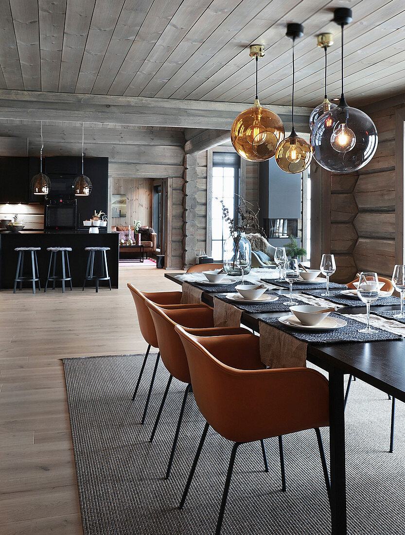 Cognac-brown chairs around set dining table in log cabin