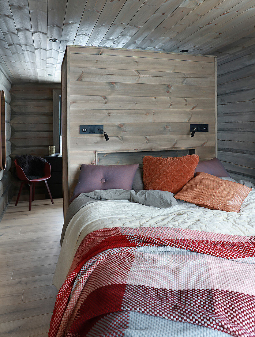 Gemütliches Bett vor einer Holzwand als Raumteiler