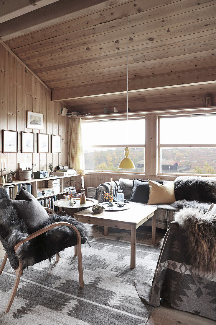 Chalet-Wohnzimmer mit grauen Accessoires und Holzverkleidung