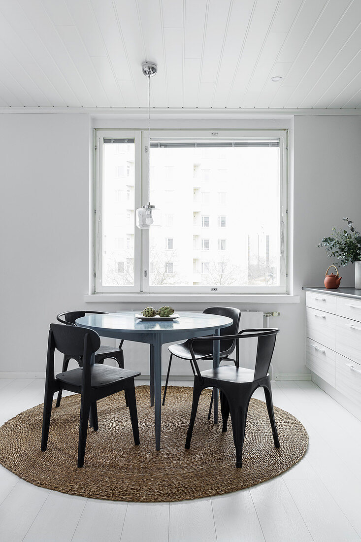 Runder Tisch mit Stühlen auf rundem Teppich vor Küchenzeile