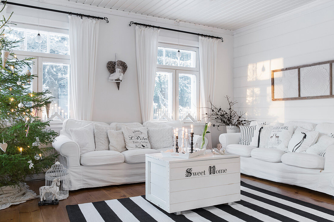 Weiße Couchgarnitur, Truhe als Couchtisch und Weihnachtsbaum im Wohnzimmer