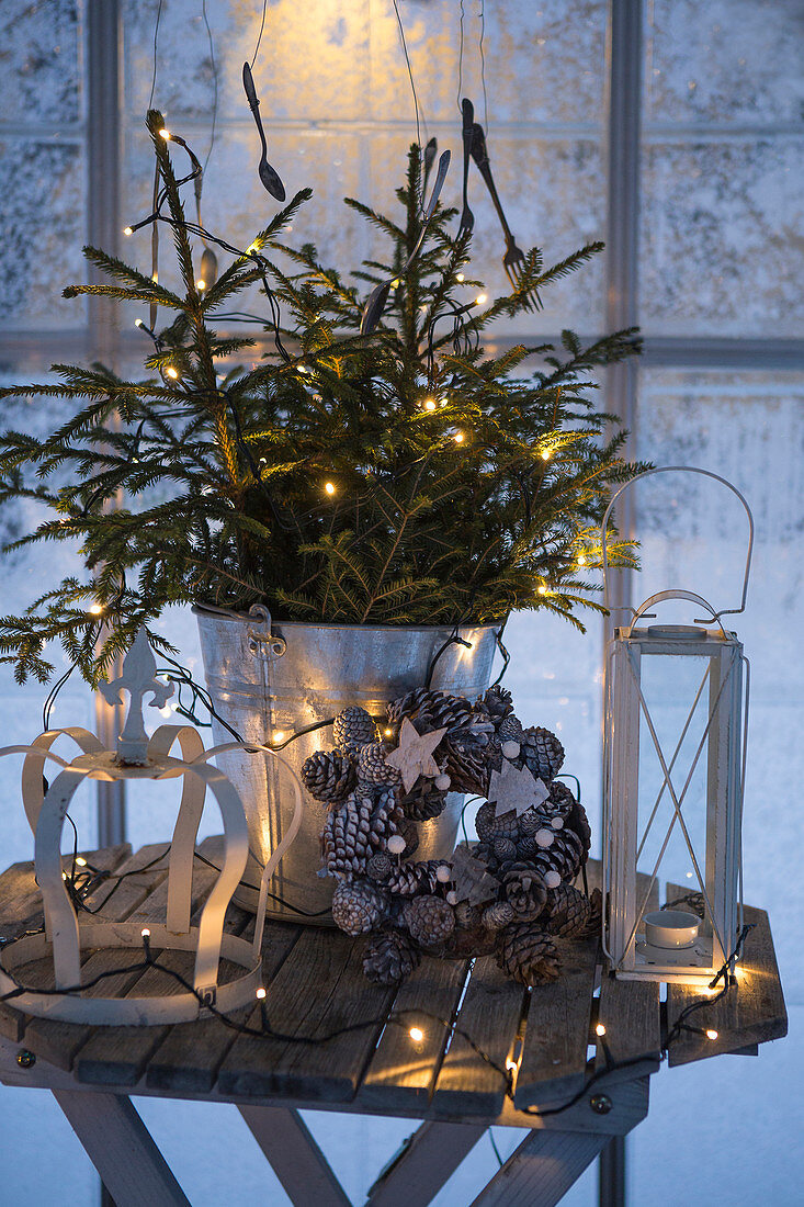 Christmas arrangement with fair lights on small wooden table in front of window