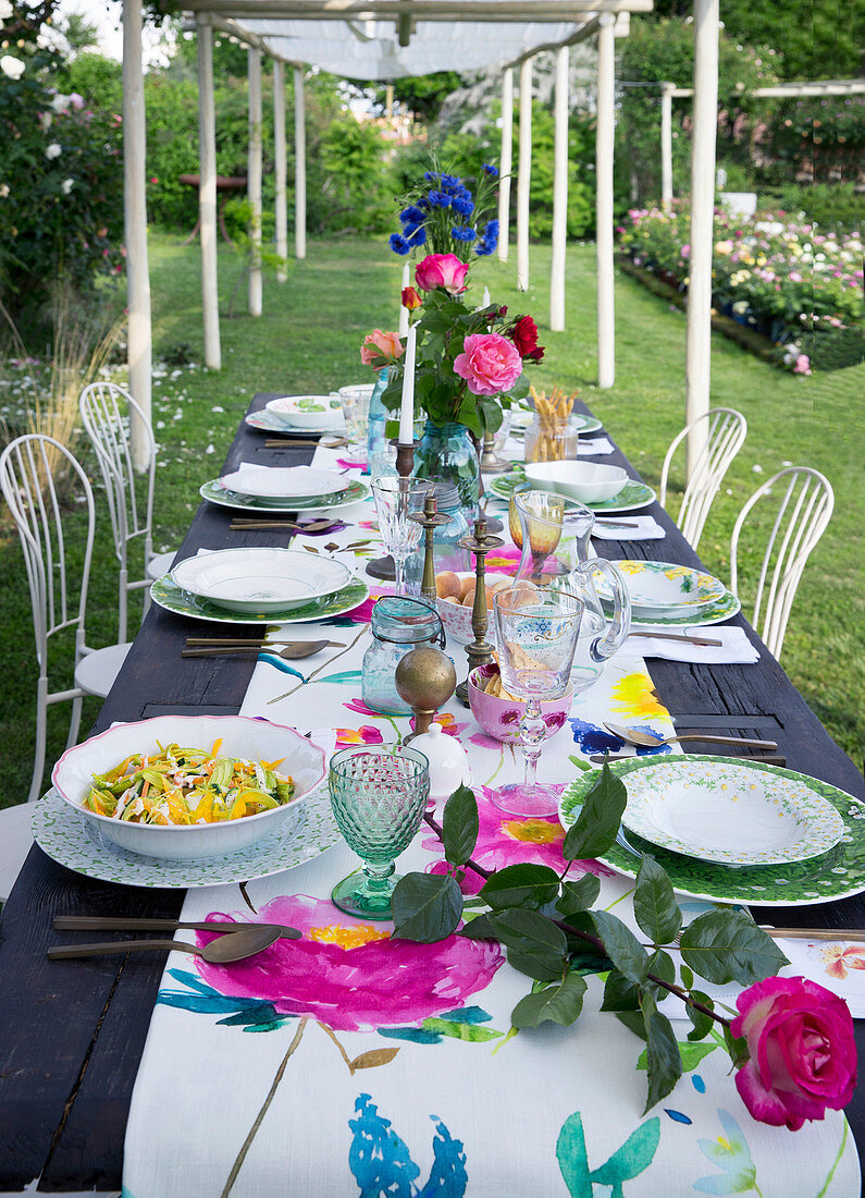 Gedeckter Tisch mit Rosendeko unter Pergola