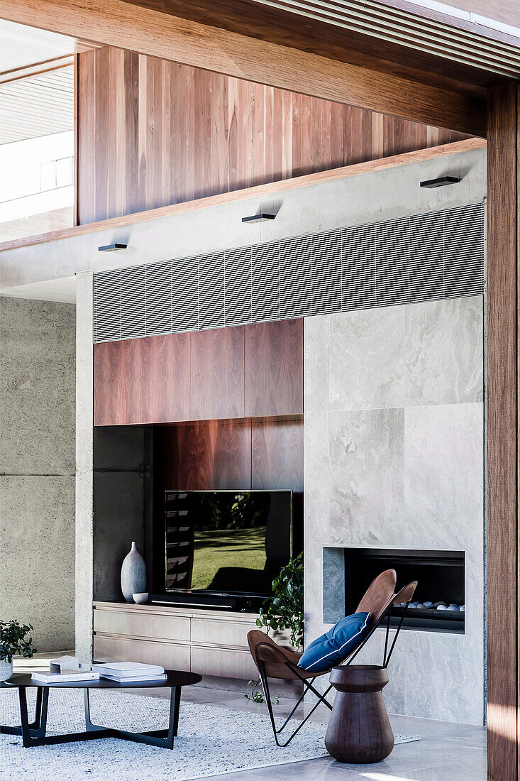 Concrete wall with integrated TV shelf and fireplace in a high living room