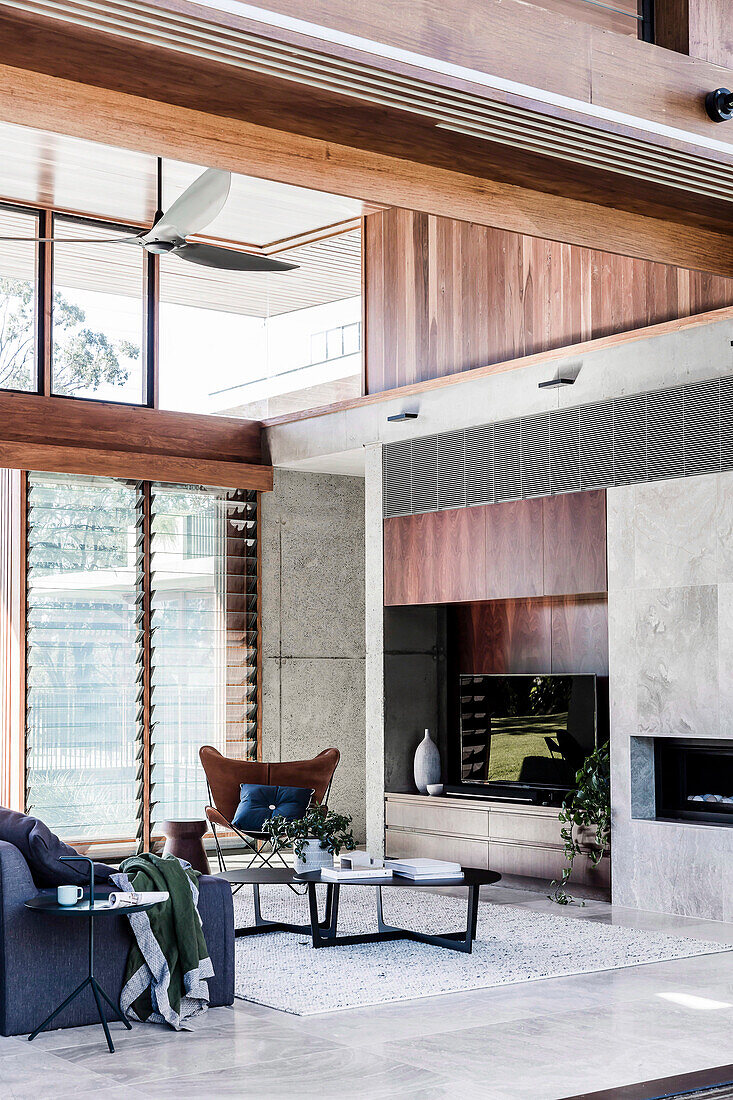 Concrete wall with integrated TV shelf and fireplace in a high living room