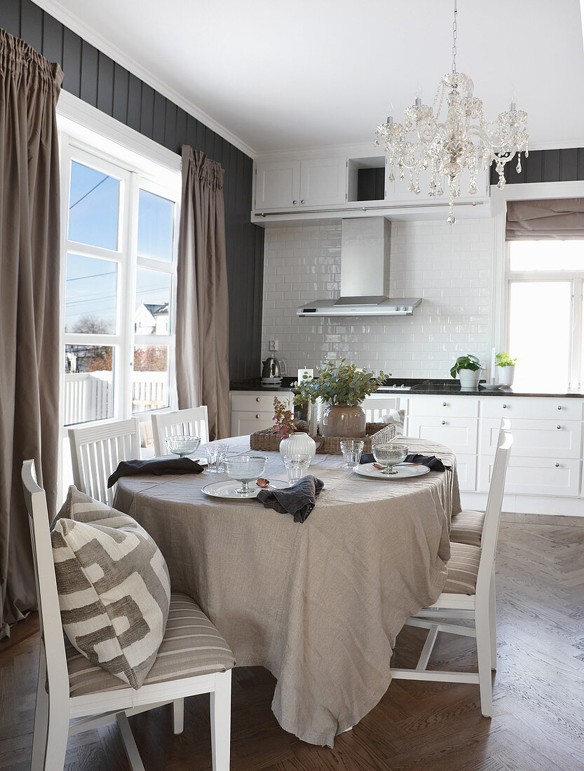 Esstisch mit Leinendecke und Stühle in heller Küche