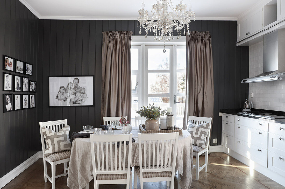Esstisch mit Leinendecke und Stühle unter Kronleuchter in Küche dunklen Wänden