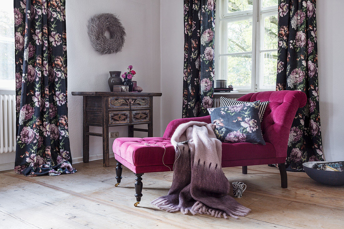 Pink recamier in front of windows with dark floral curtains
