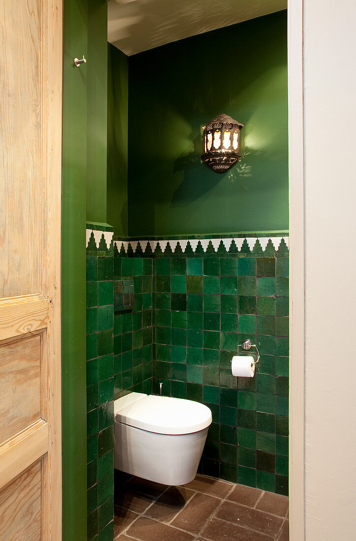 Toilet in room with Oriental-style green walls
