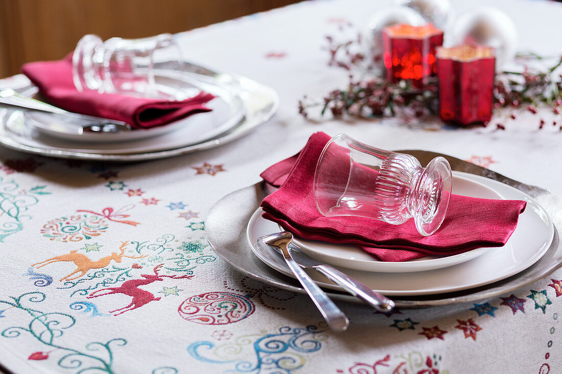 Place settings with red napkins on festive tablecloth