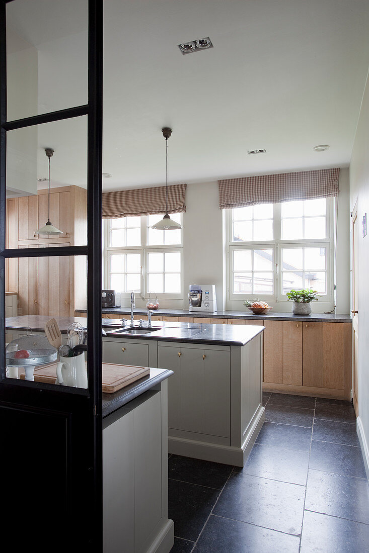 Blick auf Mittelblock und Unterschrank mit Holzfront vor Fenster in eleganter Küche