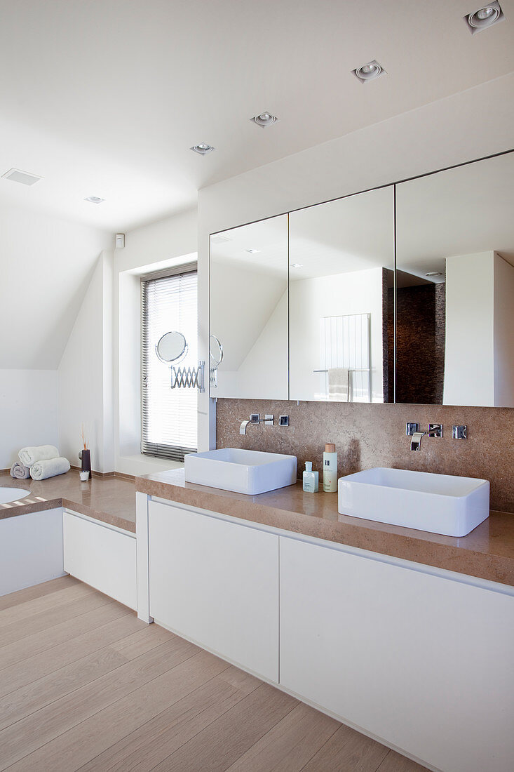 Waschtischmöbel mit zwei Aufsatzbecken und Natursteinplatte, darüber Spiegelschrank in minimalistischem Badezimmer