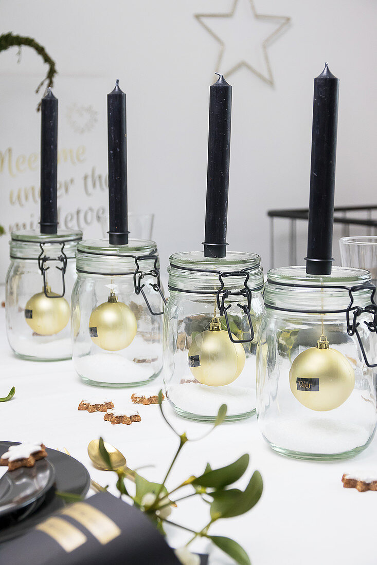 Black candles on mason jars with Christmas-tree baubles inside