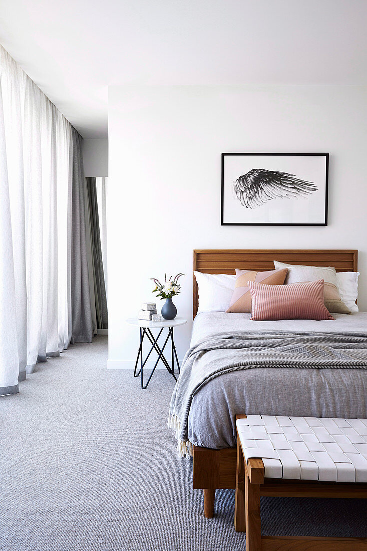 Einzelbett im hellen Schlafzimmer mit grauem Teppichboden