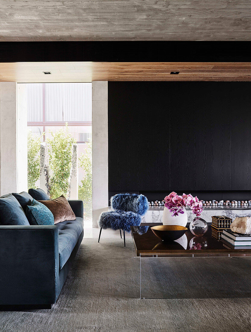 Blue upholstered sofa, fur-look chair and coffee table in open living room