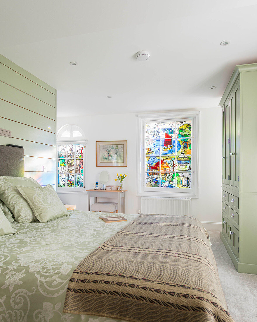 Schlafzimmer mit hellgrünen Möbeln und Buntglasfenstern
