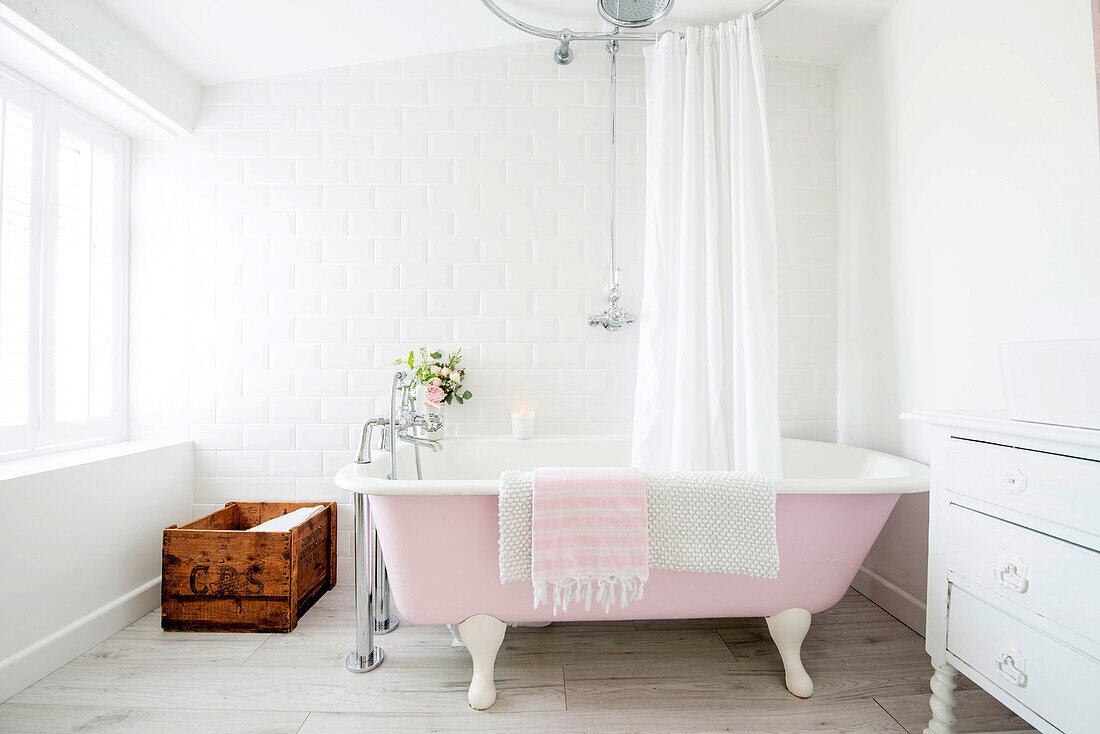 Pink free-standing bathtub in white bathroom