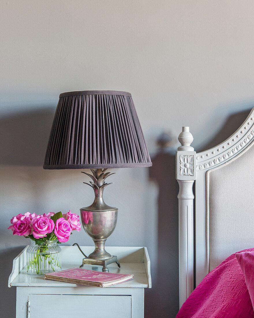 Pink roses and vintage-style lamp on bedside table
