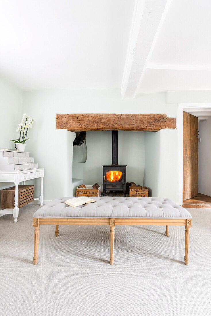 Couch in front of log-burner in old inglenook fireplace in rustic living room