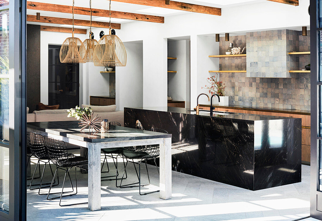 Kücheninsel aus schwarzem Granit, Esstisch und Klassikerstühle in offenem Wohnraum