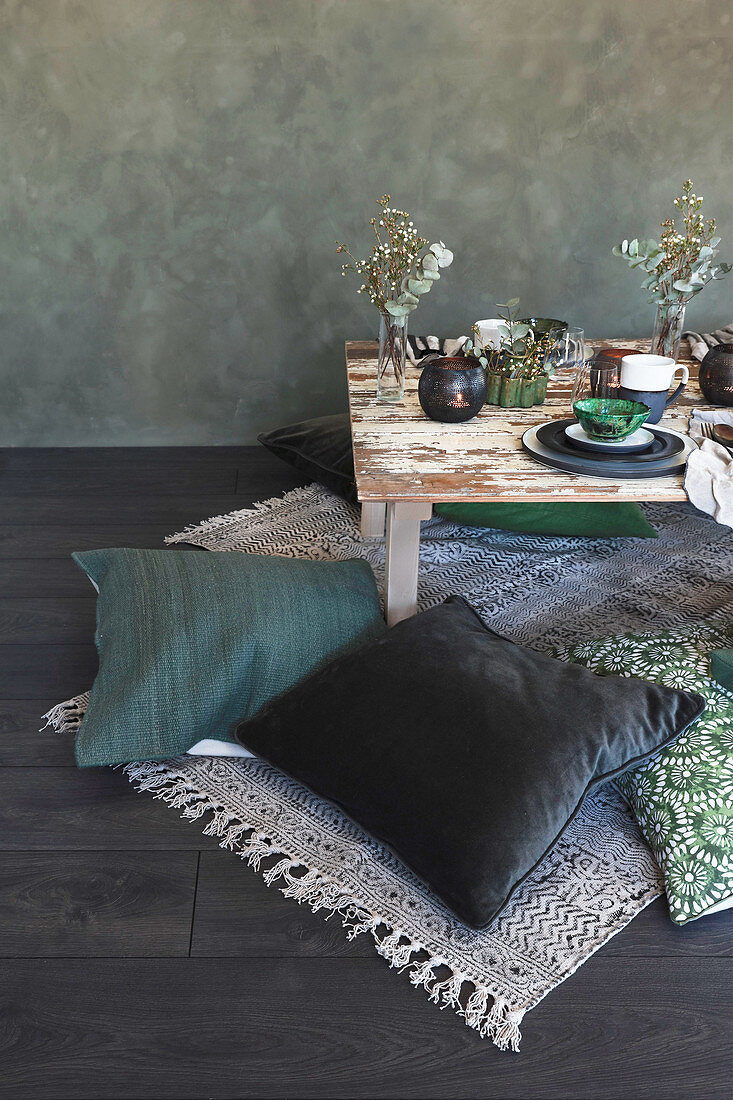 Green cushions on floor around low table with place settings