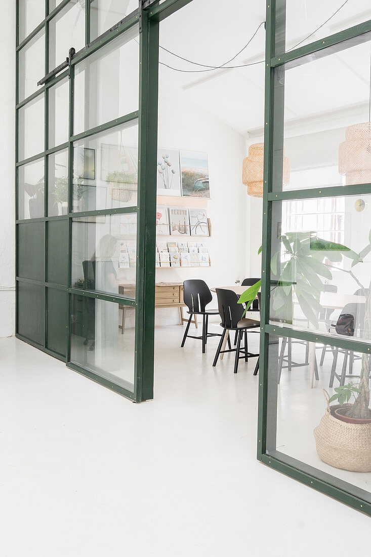 Sliding door in glass-and-steel wall leading into vintage-style conference room