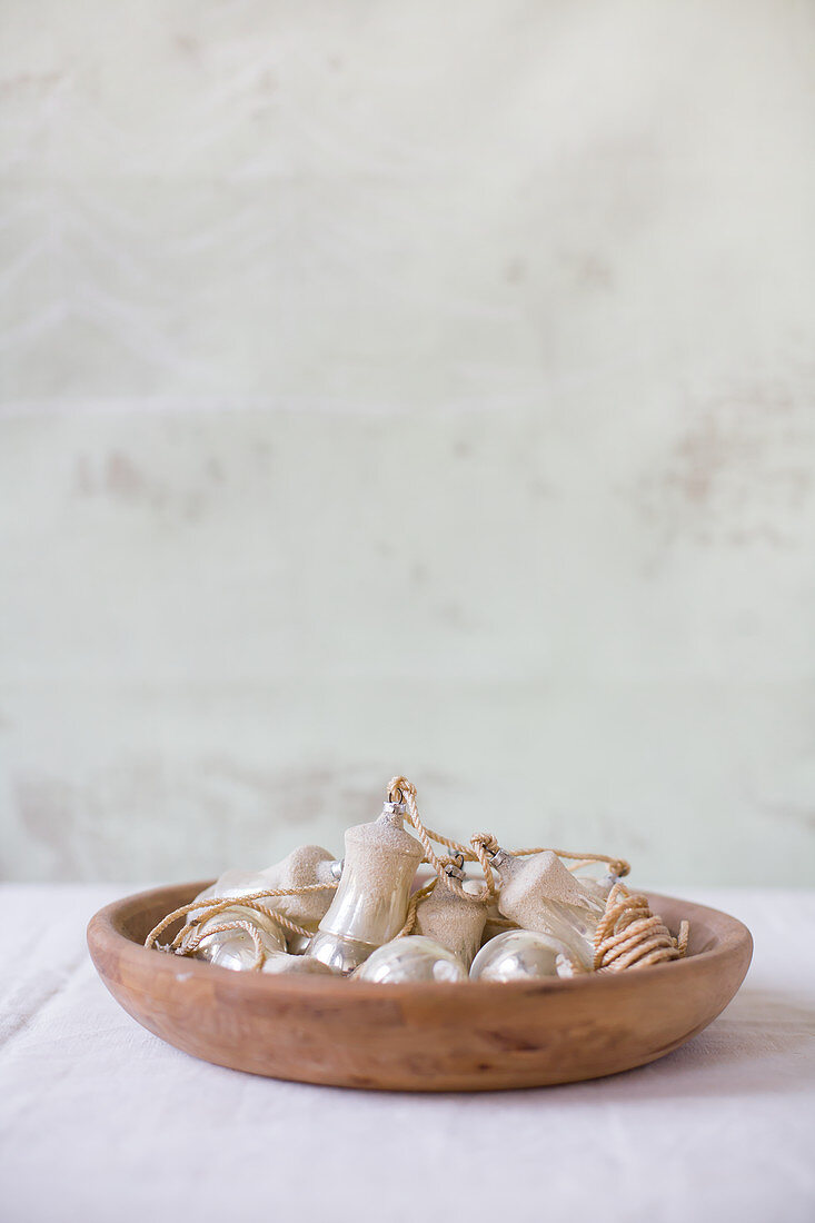 Silver Christmas baubles in wooden bowl
