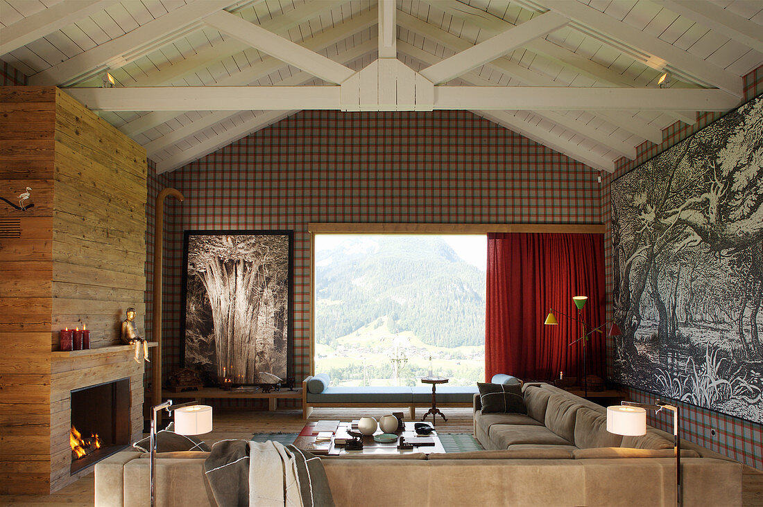 Fireplace and wood-panelled wall in elegant living room with panoramic view of landscape