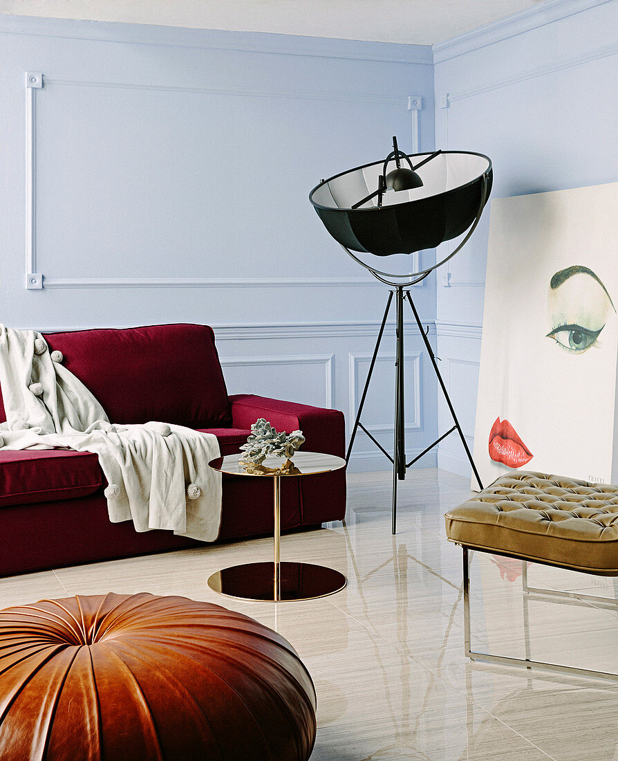 Dunkelrotes Sofa, Replik von Klassikerstehlampe, Beistelltisch Lederstuhl und Lederpouf im Wohnzimmer