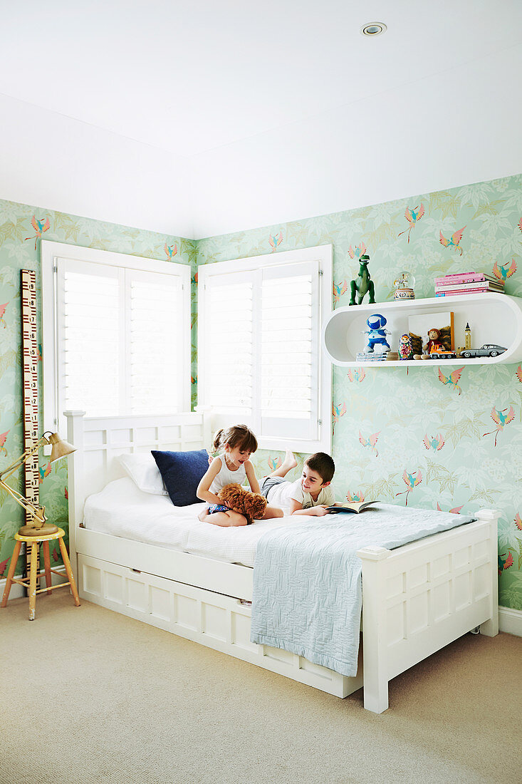 Children on the bed in the children's room with mint green wallpaper