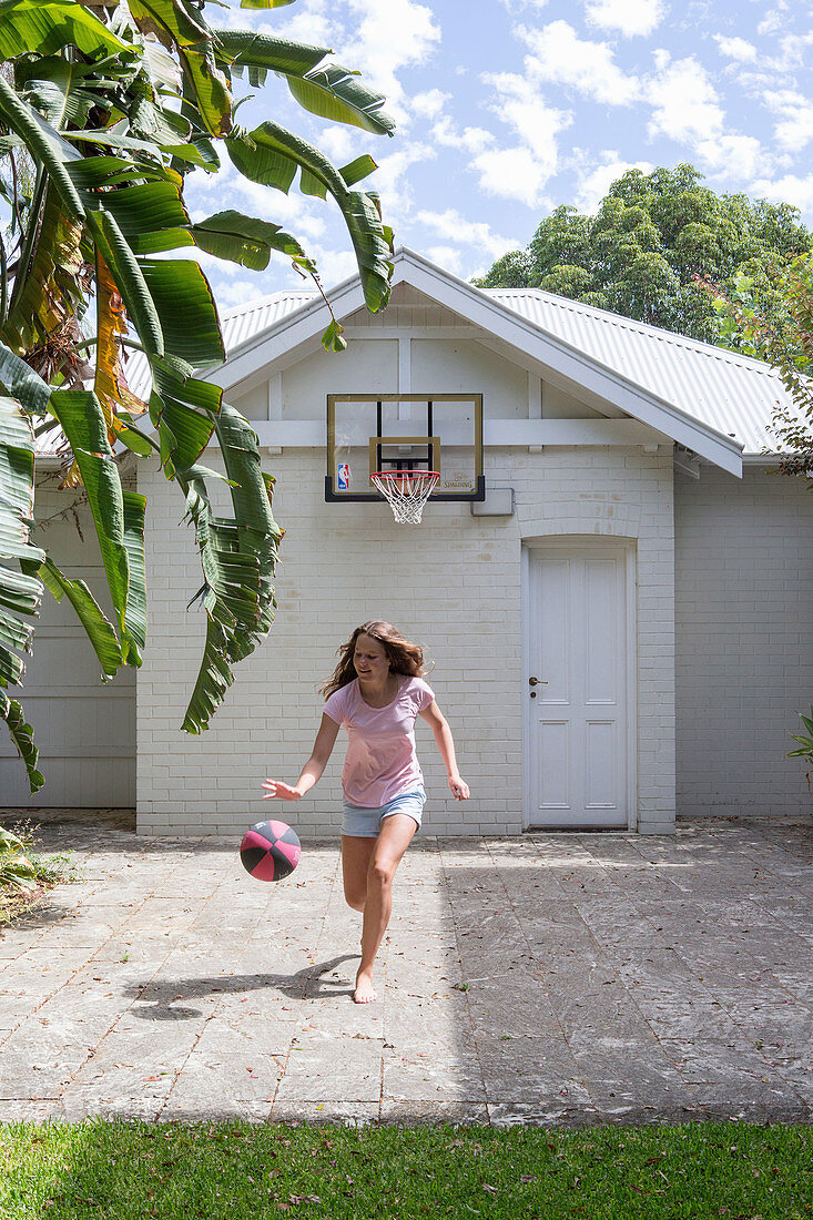 Mädchen spielt mit Basketball auf Vorplatz
