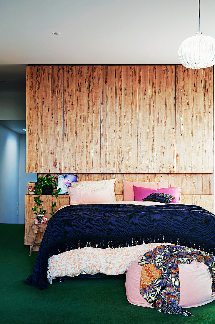 Doppelbett vor Raumteiler mit Holzverkleidung
