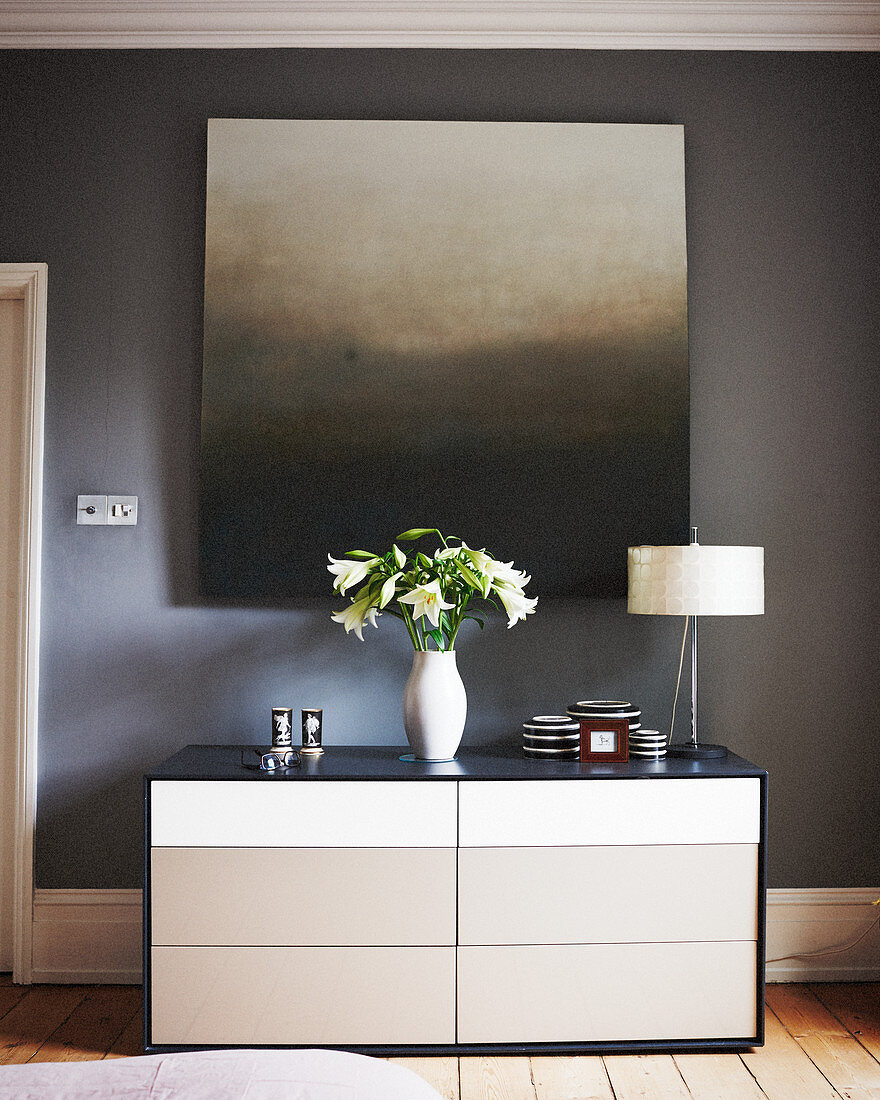 Gemälde mit Farbverlauf an grauer Wand über einer Kommode