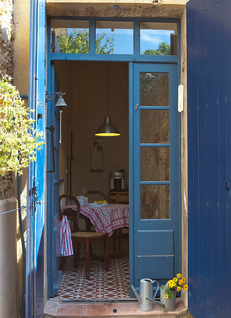 Blick durch geöffnete Terrassentür mit blau lackiertem Rahmen in Wohnküche