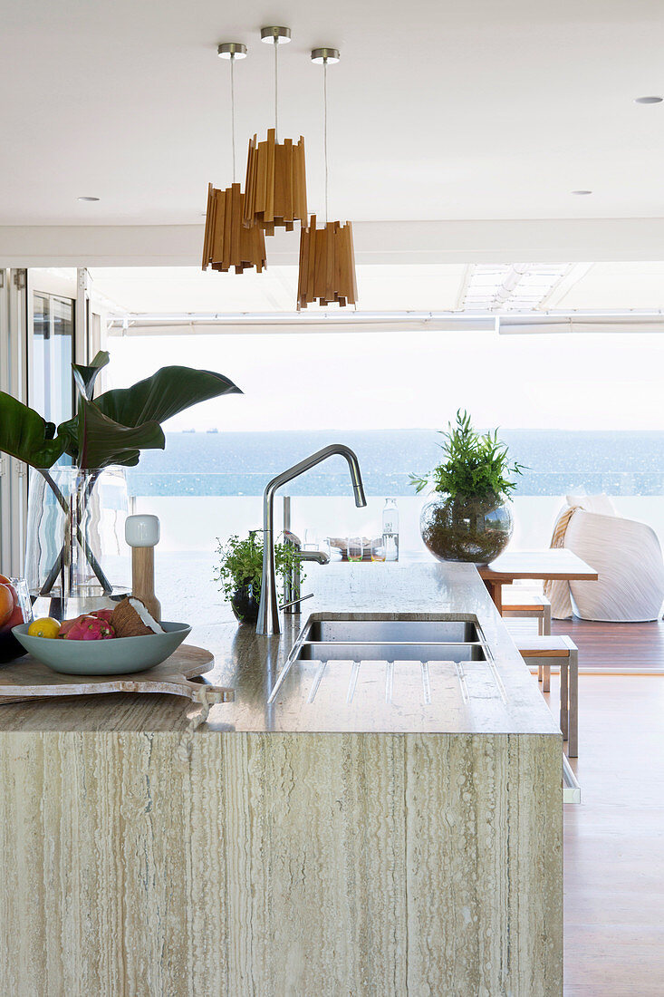 Kücheninsel mit Steinplatte; Blick auf die Terrasse und das Meer