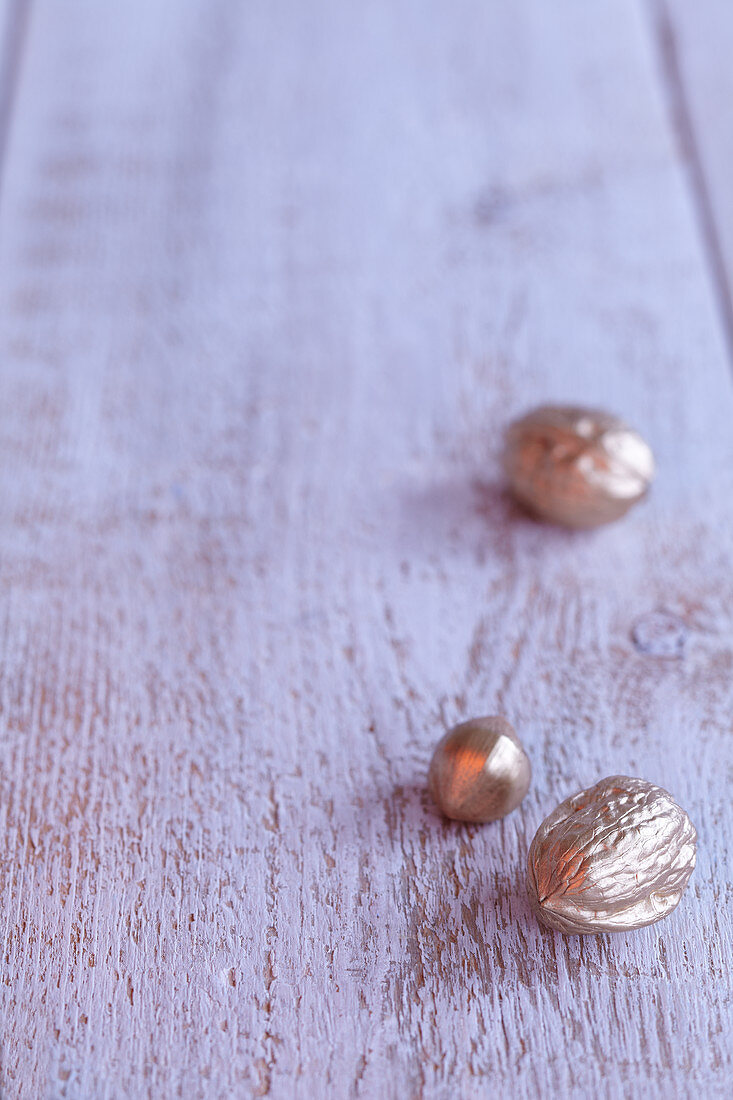 Gold walnuts and acorn on wooden surface