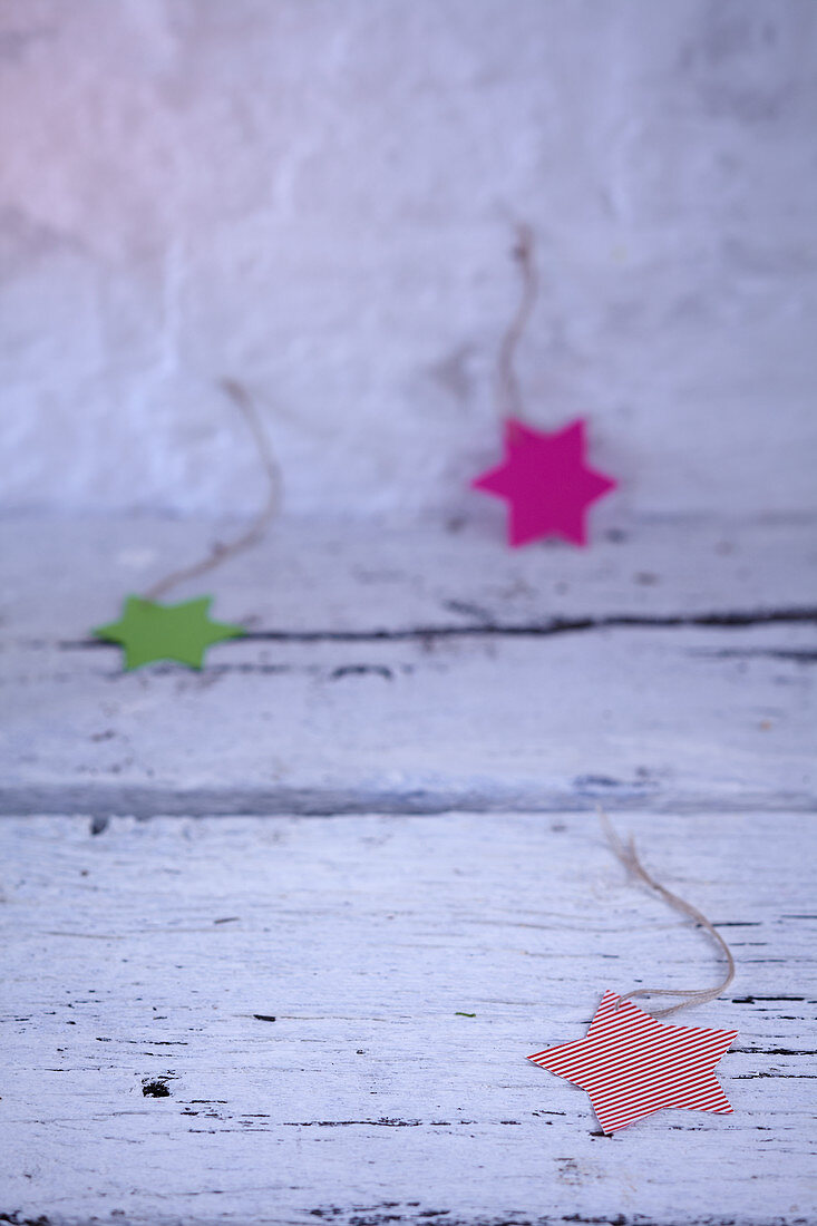Paper Christmas stars of various colours on ribbons