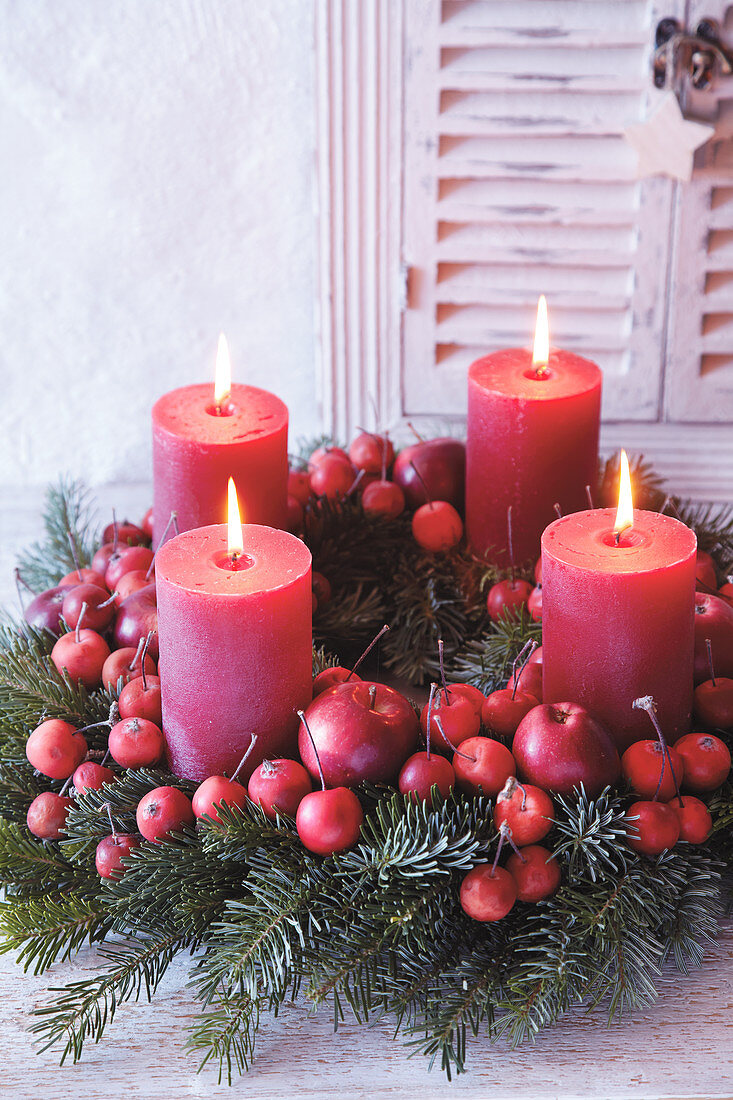 Advent wreath made from red crab apples and red pillar candles