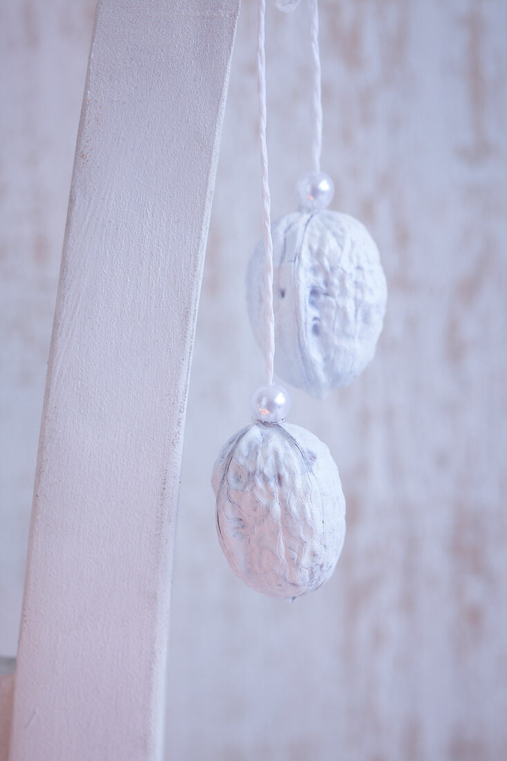 White-painted walnuts decorated with pearls and hung up as Christmas decorations
