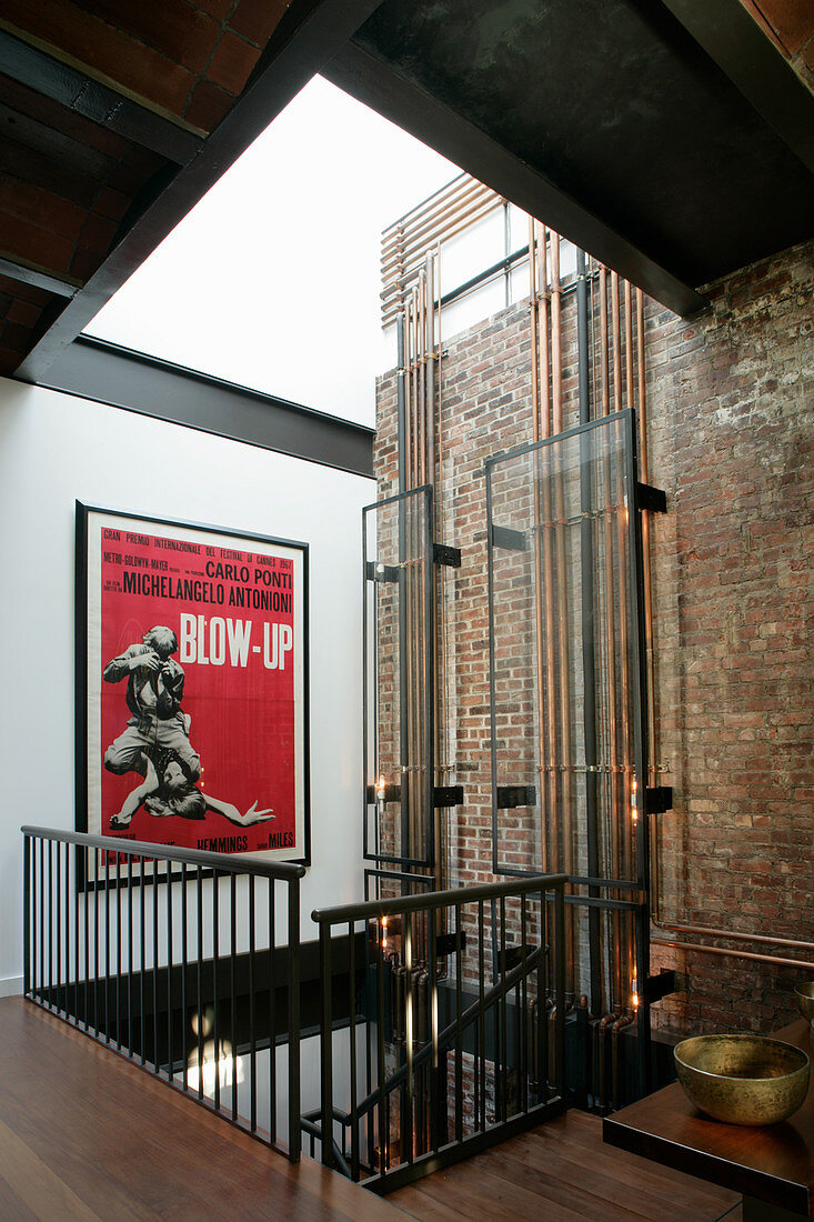 Glass panels covering copper pipes and film poster in stairwell