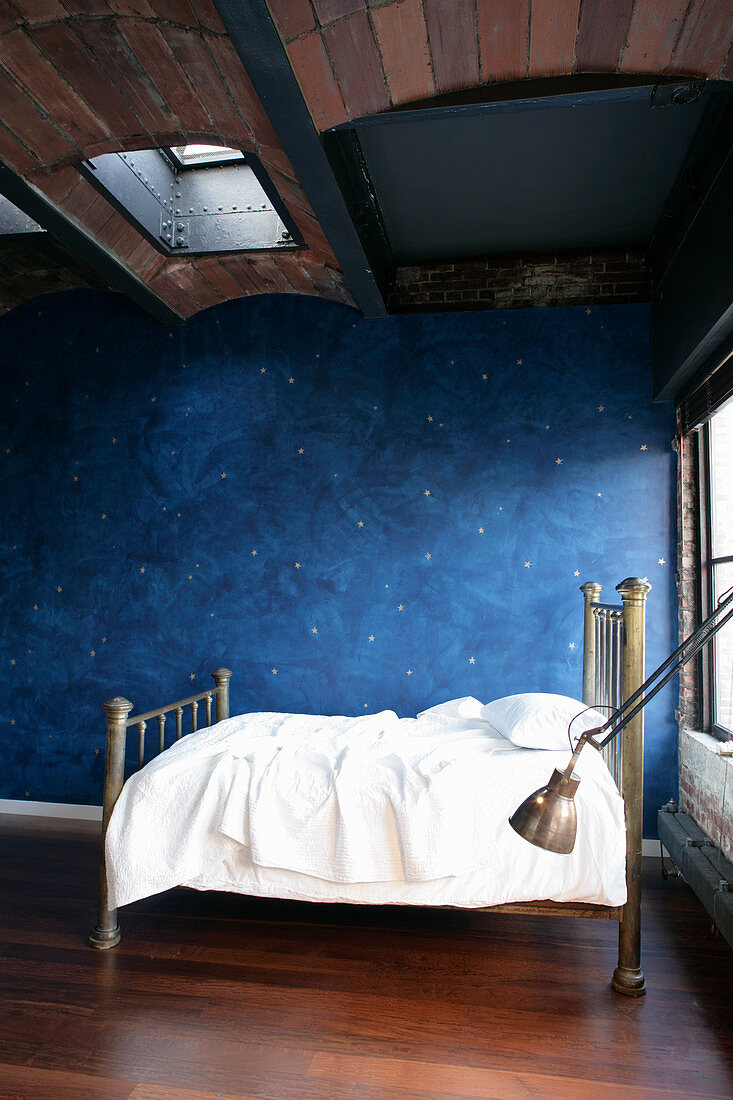Child's bed against blue wall with pattern of stars below vaulted ceiling