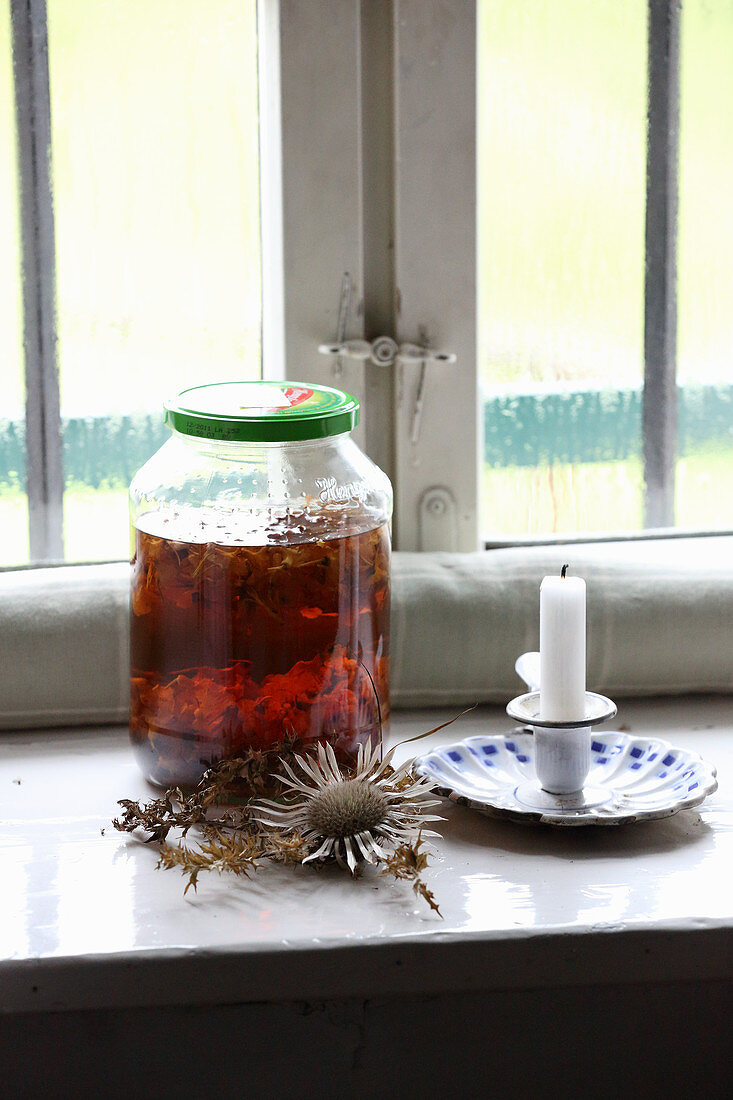 Jar of homemade St. John's wort oil for healing wounds on windowsill